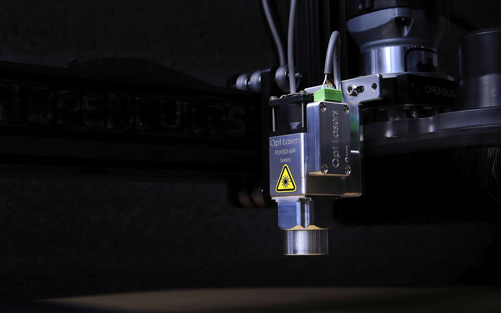 A faceting machine in use: dop arm, rotating lap, and an adult cutter's hands and face lit by the work lamp
