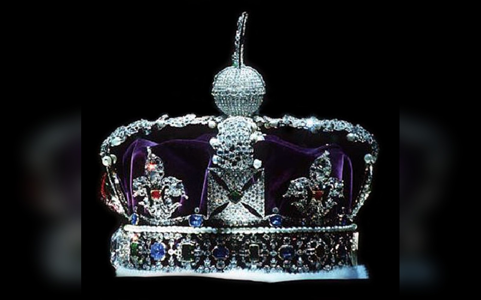 A jewel-encrusted crown with purple velvet cap, pearls, sapphires, and a large red gem on its band