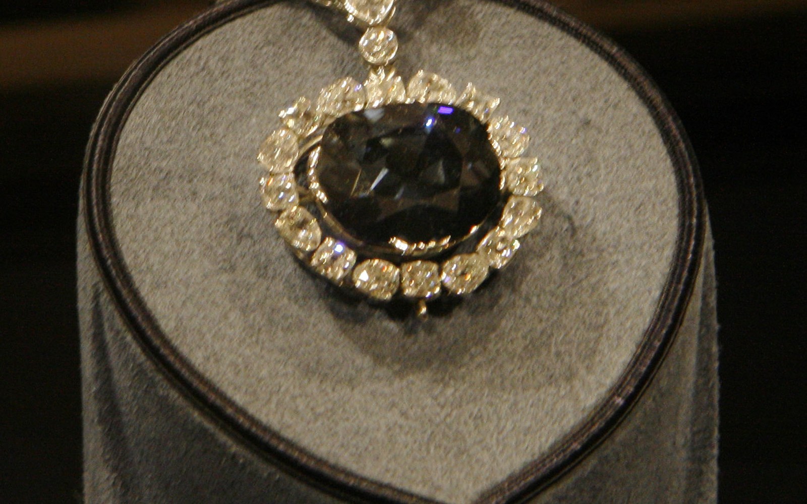 Large blue diamond pendant surrounded by white diamonds on a display mount