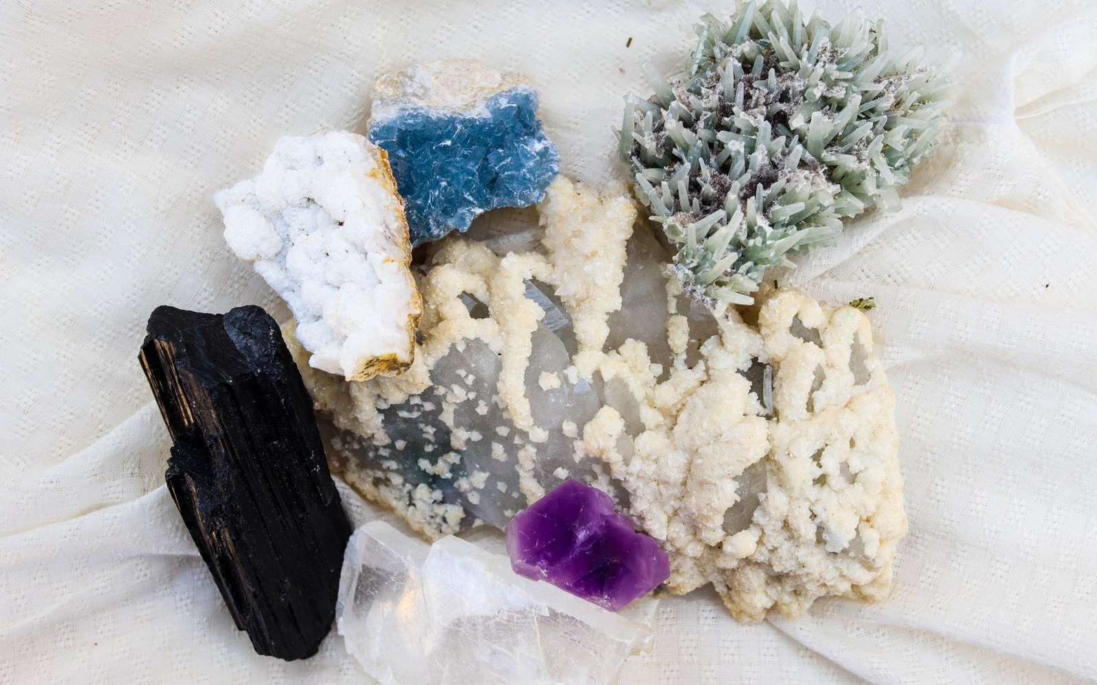 Assorted mineral specimens including black tourmaline, purple fluorite, and blue and white crystals