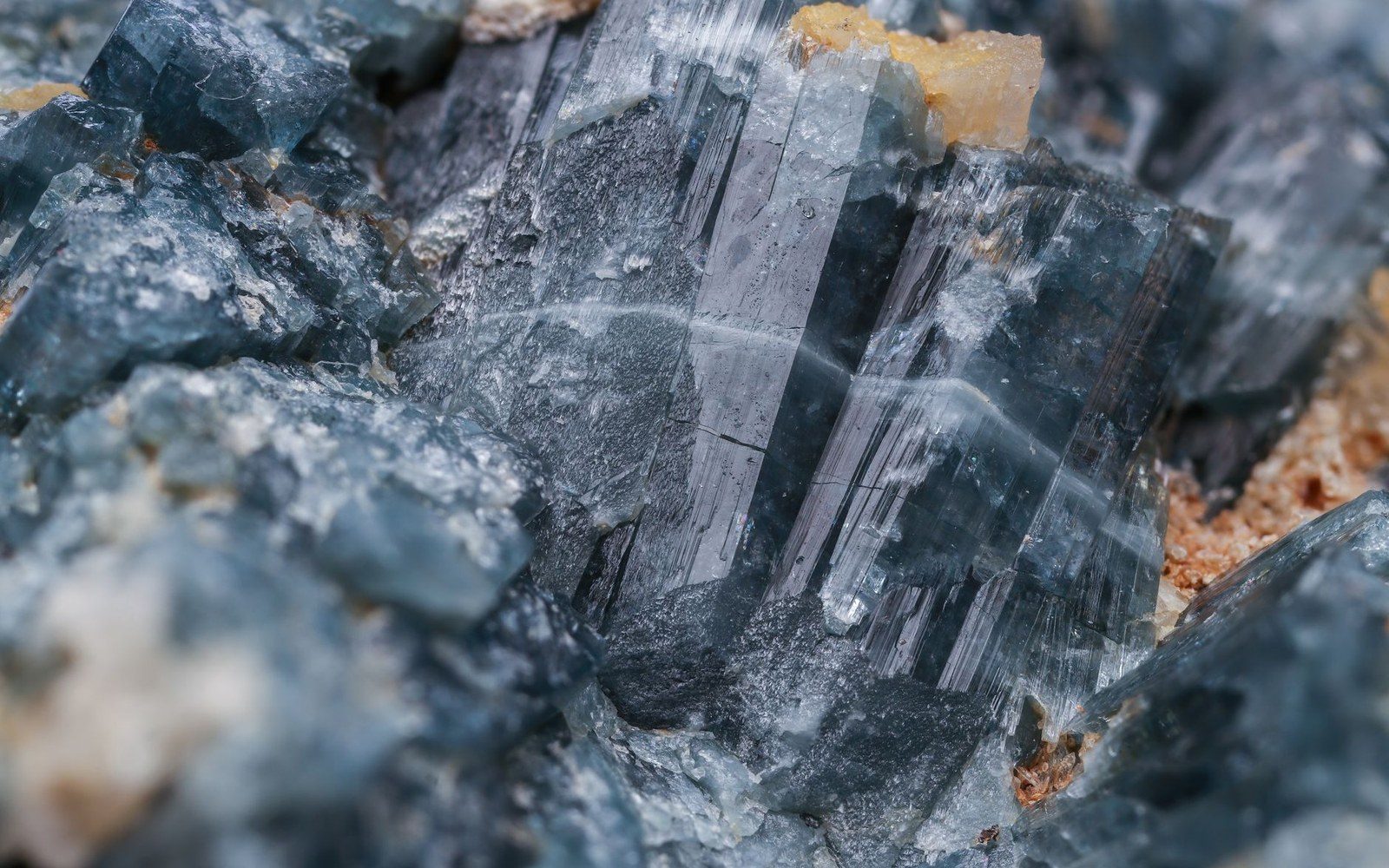Close-up of striated bluish-grey tourmaline crystals embedded in rough matrix rock