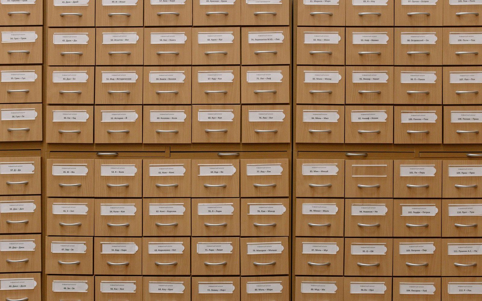 An open museum specimen drawer with labelled gem specimens in numbered compartments, handwritten catalogue cards beside each tray